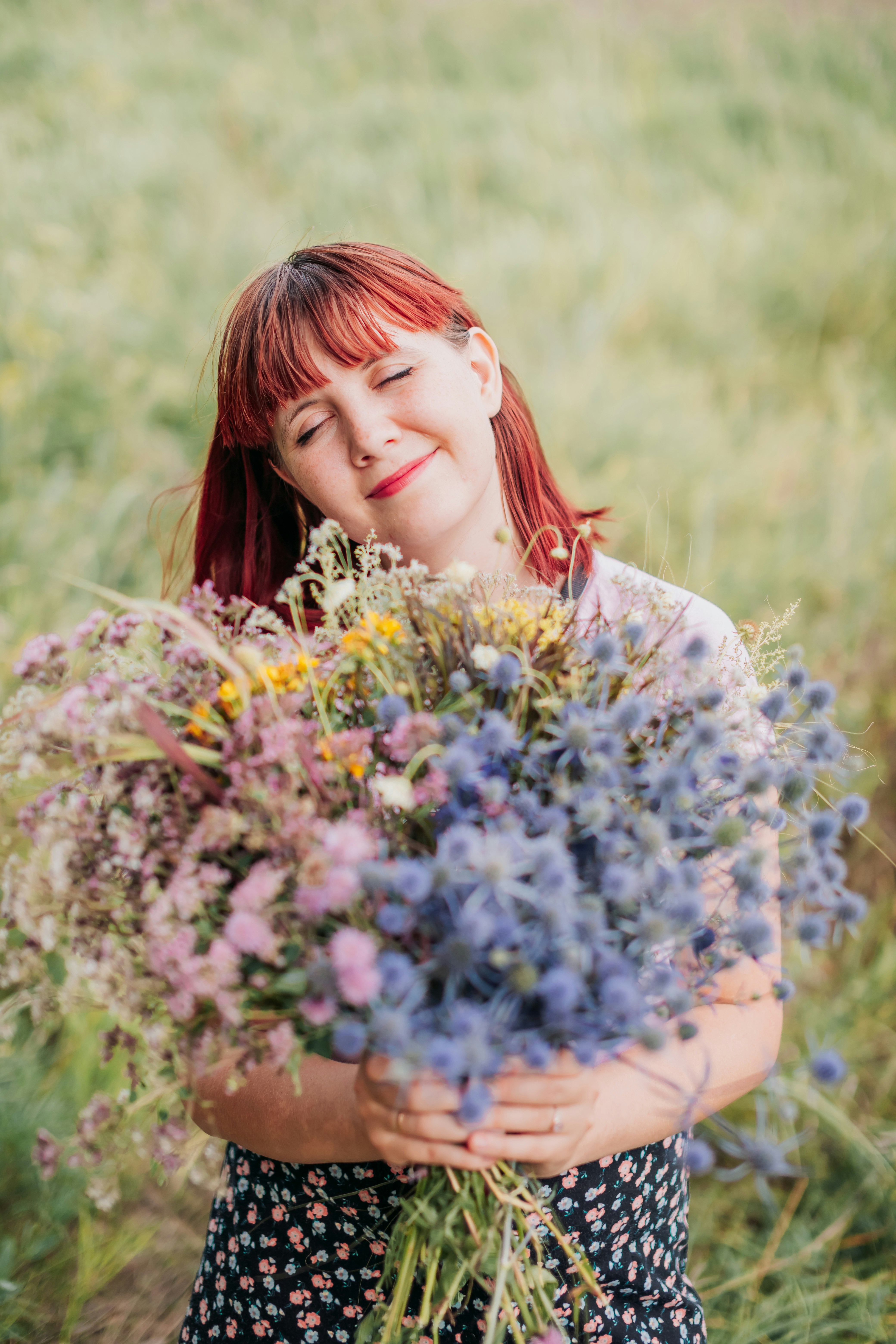 woman in white floral dress holding blue flowers